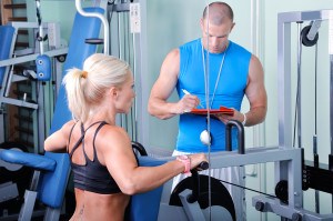 Woman in gym exercising with personal fitness trainer