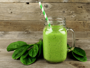 Green smoothie with spinach on wood